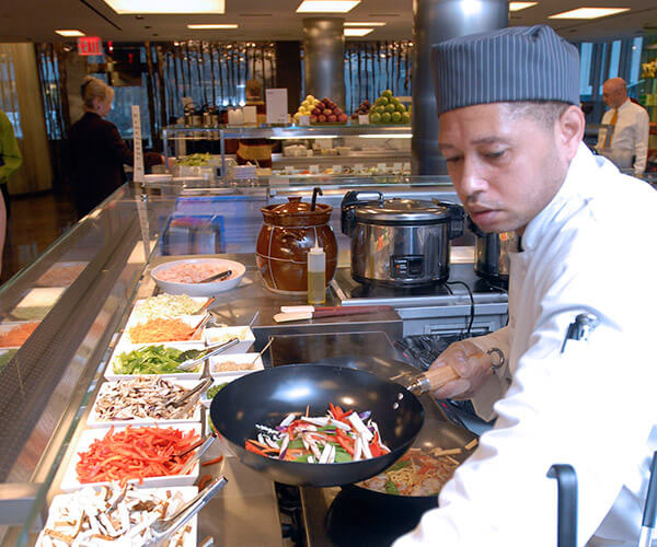 a man in a chef’s hat stands over a counter with food