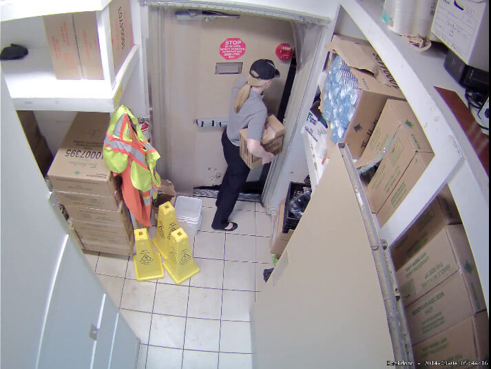 a woman carries a box out the back door of a restaurant. Video surveillance can help uncover employee theft