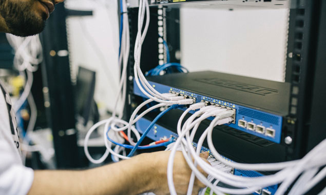 A technician connects wires to a server.