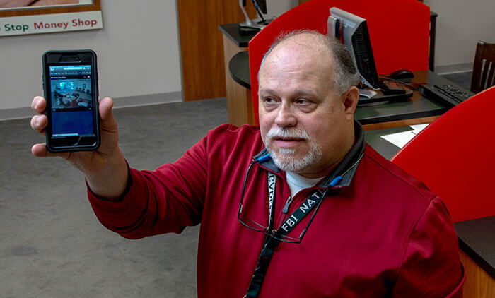 Bill Dyer, Director of Safety and Security for Check Into Cash, holds his phone that displays video surveillance images