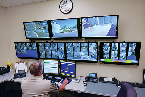 a man looks at a video wall with multiple monitor displaying surveillance images