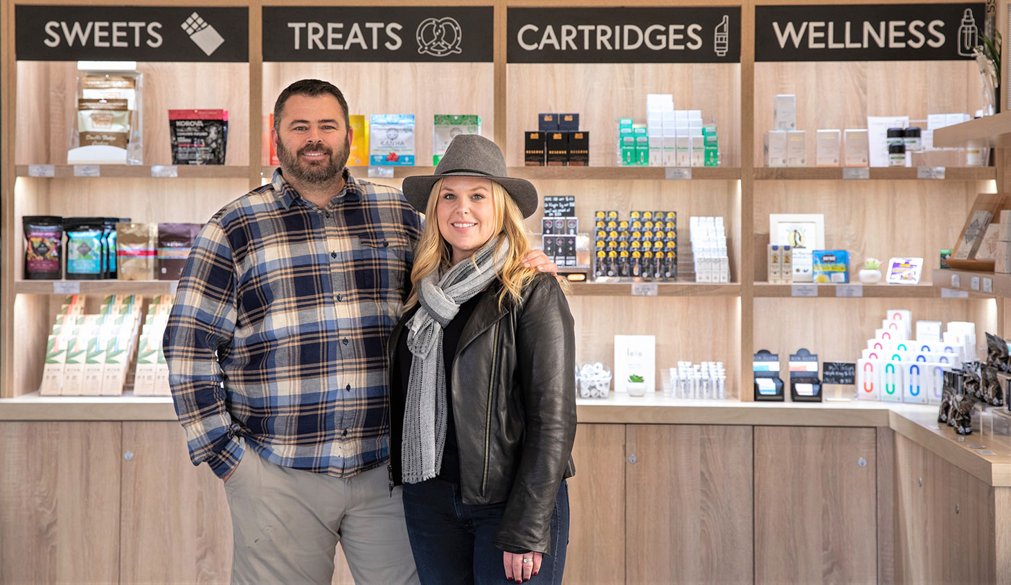 Inside Flora Terra store with owners, David and Alicia Wingard, posing and smiling in front of sign