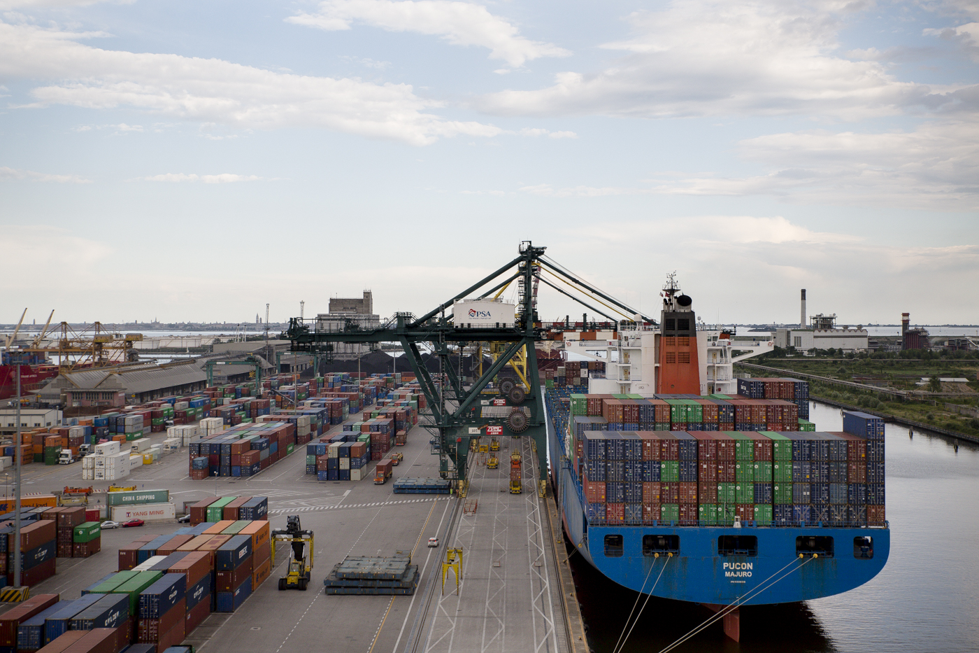  A commercial ship next to the loading dock that is filled with cargo containers at Porto Marghera