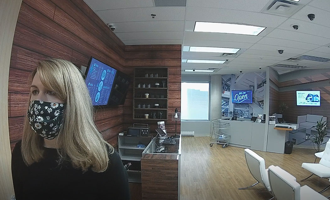 Video snapshot from a covert camera of a person wearing a mask from eye-level view in a retail environment.