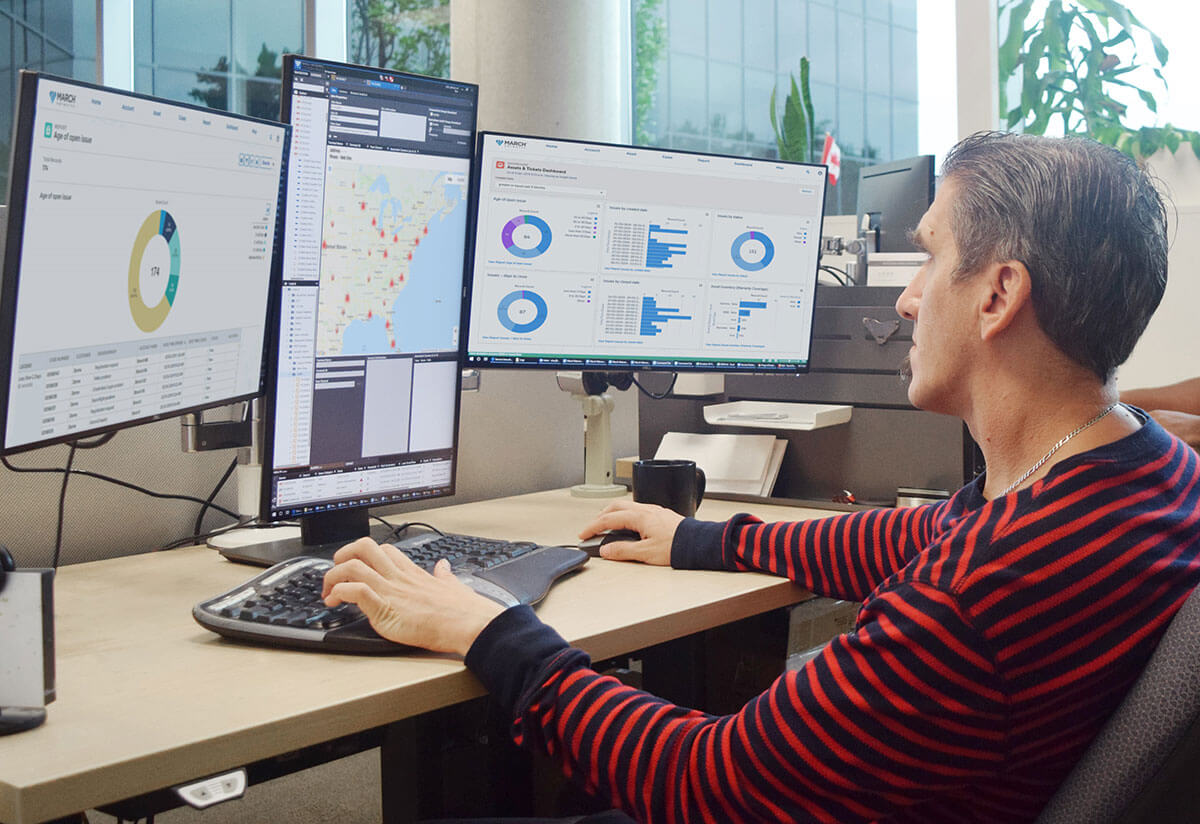 A person sitting at a desk with three computer monitors which show March Networks Insight software being used