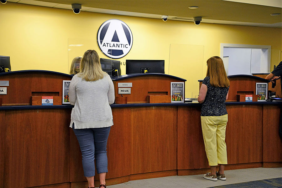 Clients standing in front of a desk speaking with tellers with visible March Networks cameras mounted to the ceiling at an Atlantic Federal Credit Union location