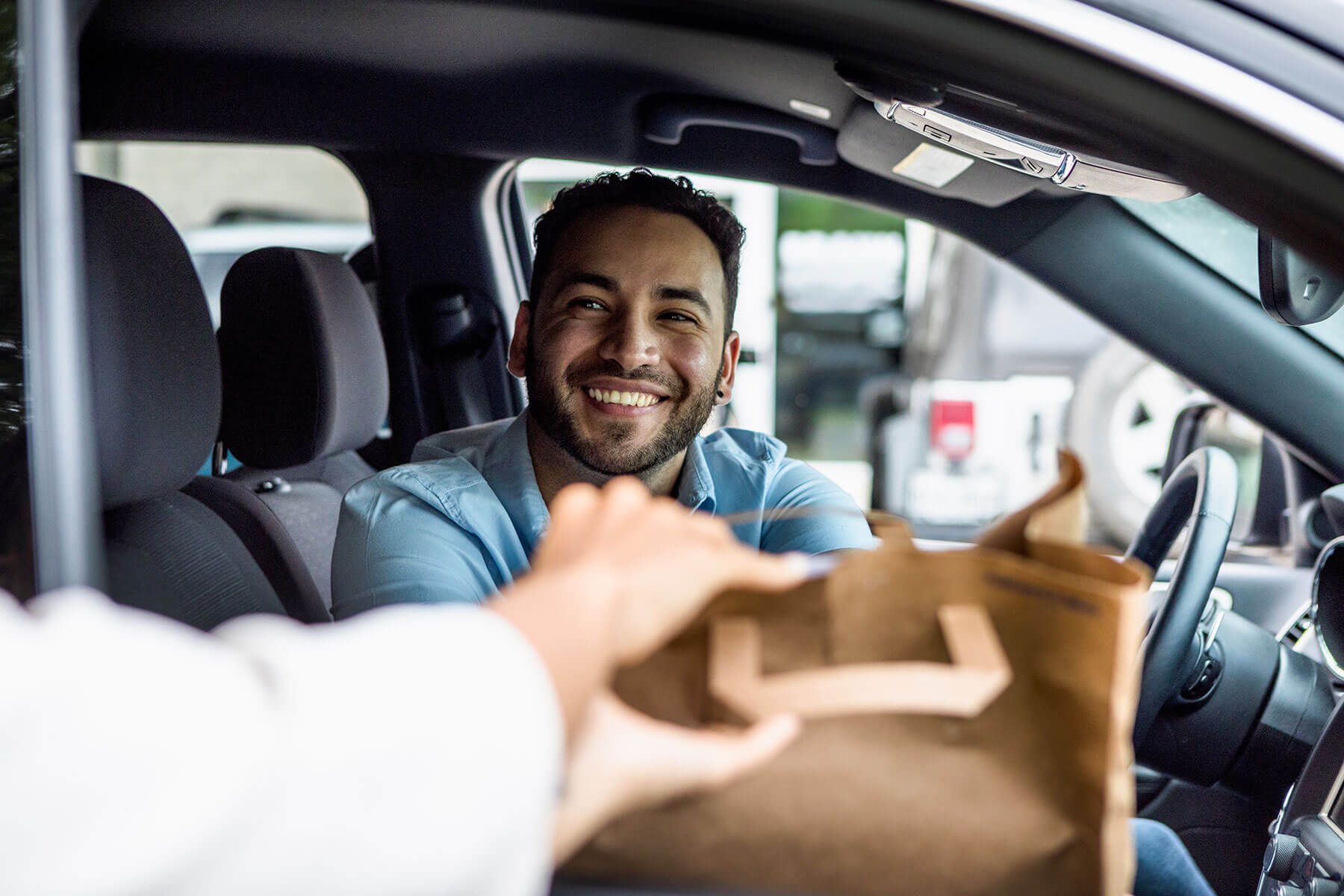 Customer in car receives order from drive-thru cashier.